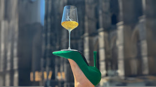 Grüner Stiletto, darauf ein Glas Wein balanciert