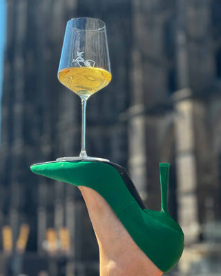 Grüner Stiletto und darauf ein Weinglas balanciert