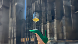 Grüner Stiletto, darauf ein Glas Wein balanciert