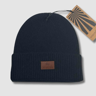 Produktfoto der schwarzen Merino Beanie Damen & Herren – flach hingelegt mit Hangtag, aus hochwertiger, weicher Merinowolle, perfekt für kalte Tage.