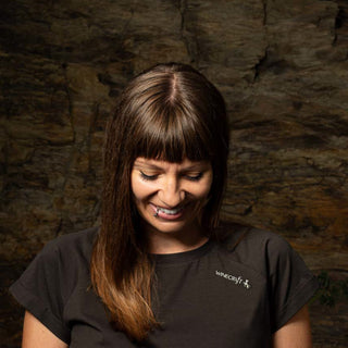 Detailaufnahme Wein T-Shirt für Damen der Marke Winecraft mit einem kleinen Logo-Print vorne auf der linken Schulter. Model lächelt schön.