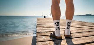 Weinsocken GRAUBURGUNDER Winecraft, weißer Tennissocken-Body, schwarzes Wording, Latschen am Strand.